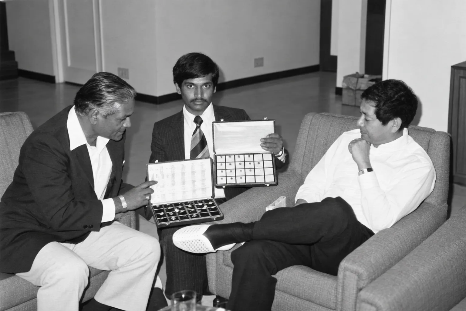 An archival photograph of a gemstone trade meeting, reviewing cases of stones